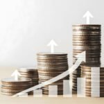 Pilhas de moedas crescendo lado a lado, com setas ascendentes que simbolizam a correção monetária e o aumento real do valor ao longo do tempo.