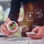 Homem revisando documentos com caneta e smartphone, marcando com um círculo verde de aprovação.