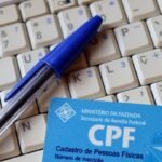 Cartão CPF sobre teclado com caneta azul