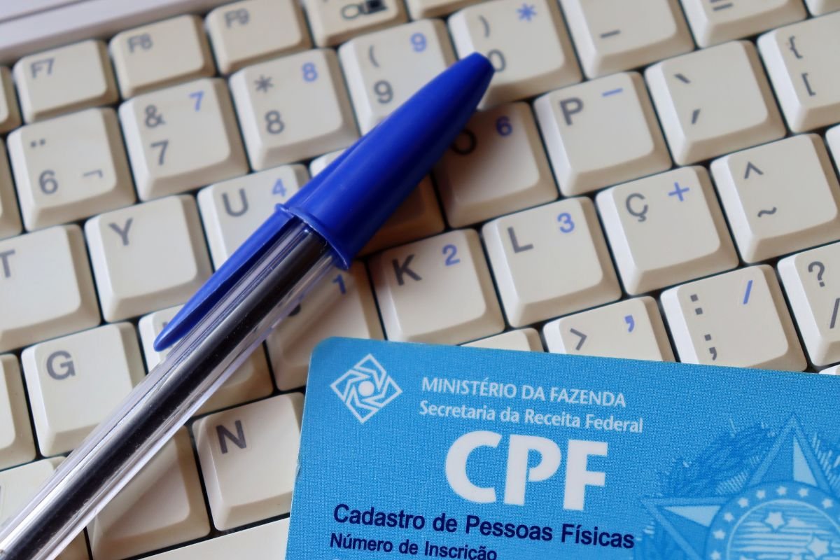 Cartão CPF sobre teclado com caneta azul